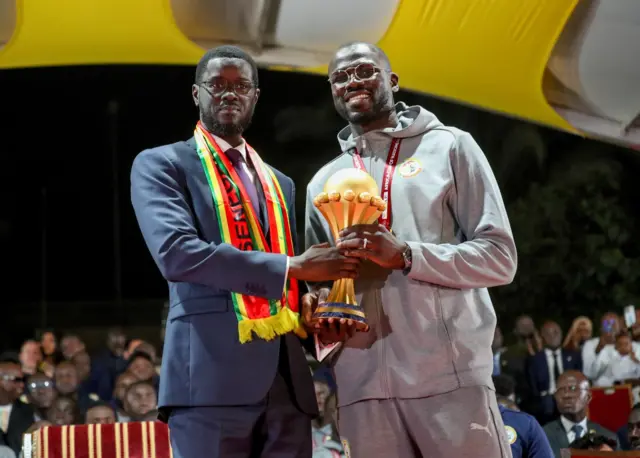 le président sénégalais Bassirou Diomaye Faye et le capitaine de l'équipe nationale Khalidou Koulibaly tenant le trophée de la coupe d'Afrique des nations